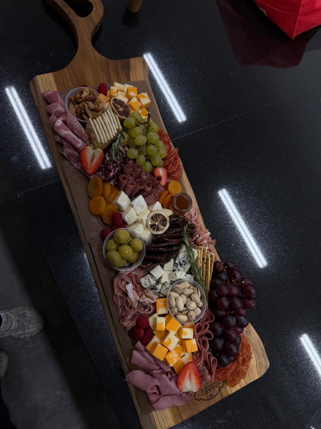 Overhead view of a MIASO board with cured meats, cheeses, fruit and nuts