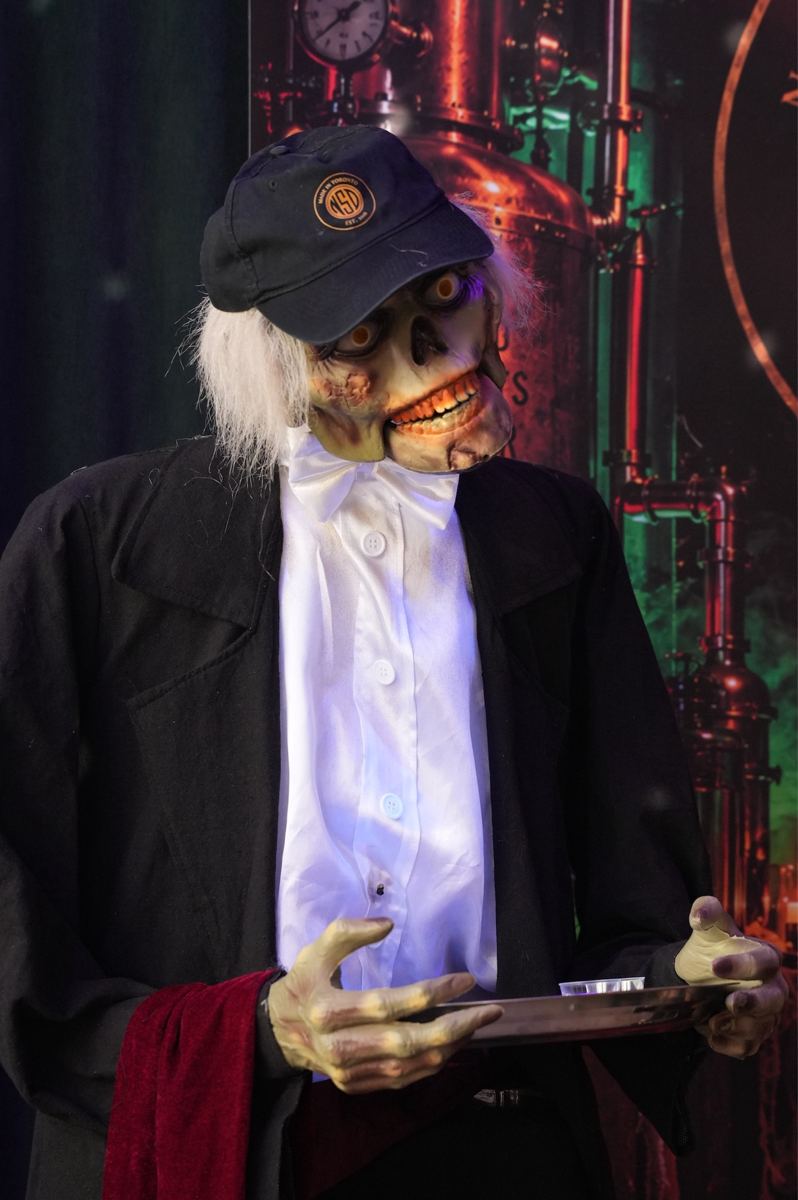 The skeletal host in a cap and bow tie